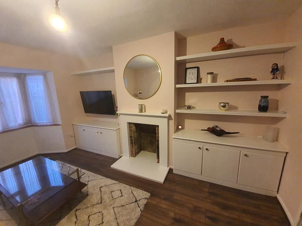 Painted alcove cupboards and floating shelves either side of a white fire surround