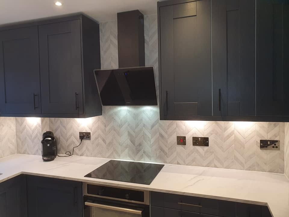 Charcoal shaker kitchen with chevron marble-effect splashback, white worktop and angled extractor