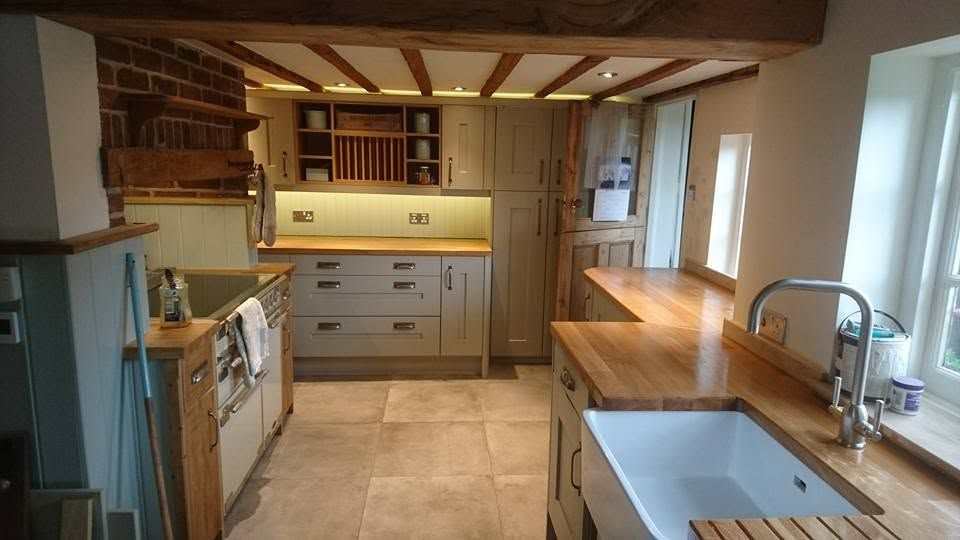 Cottage kitchen with sage shaker units, oak worktops, butler sink, plate rack and exposed ceiling beams