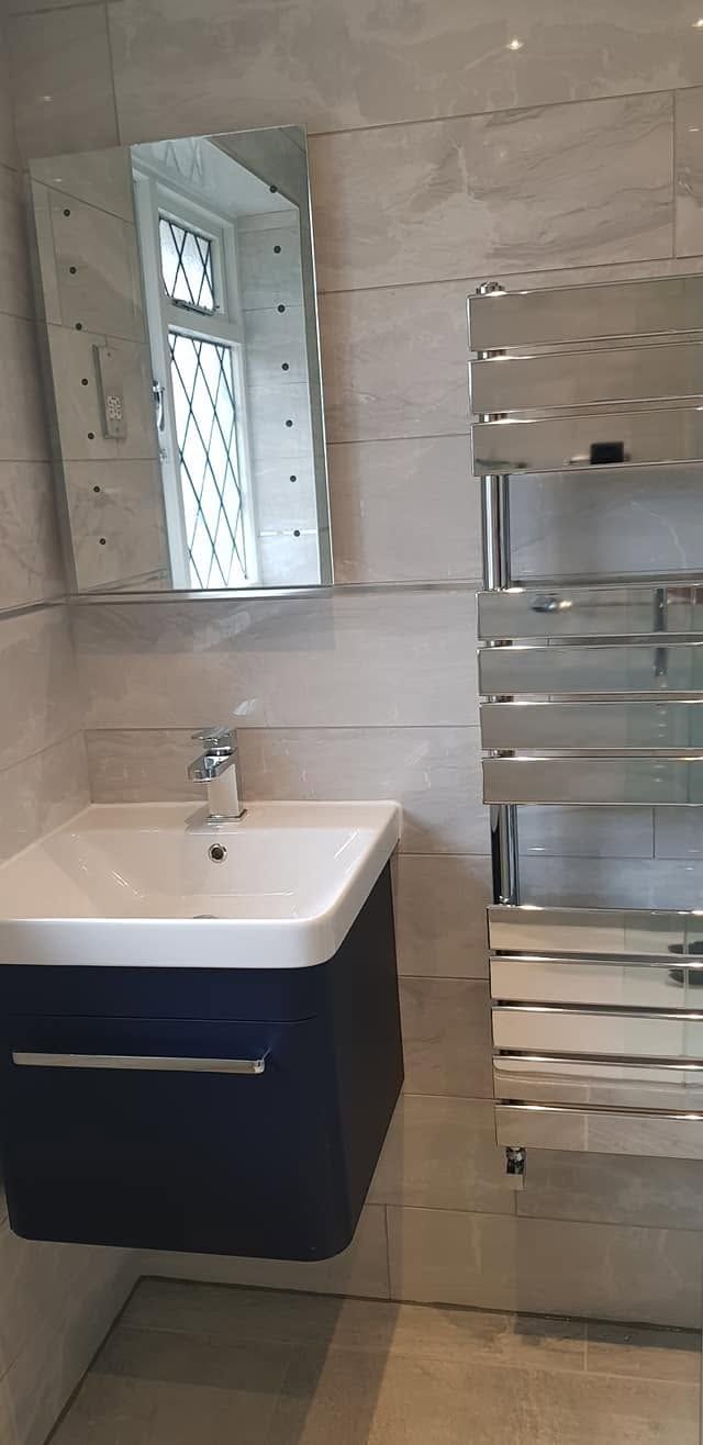 Navy wall-hung vanity with white basin and chrome mixer, mirror and chrome flat-panel towel radiator