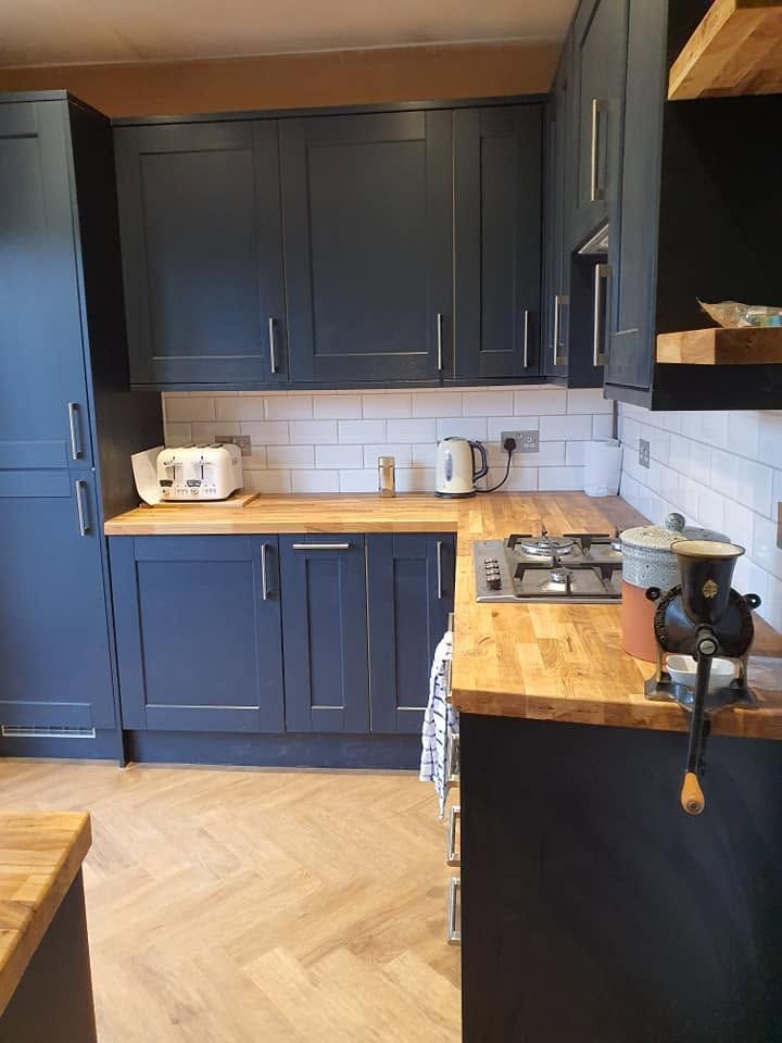 Navy shaker kitchen with solid oak worktops, gas hob, white metro tiles and herringbone-effect floor
