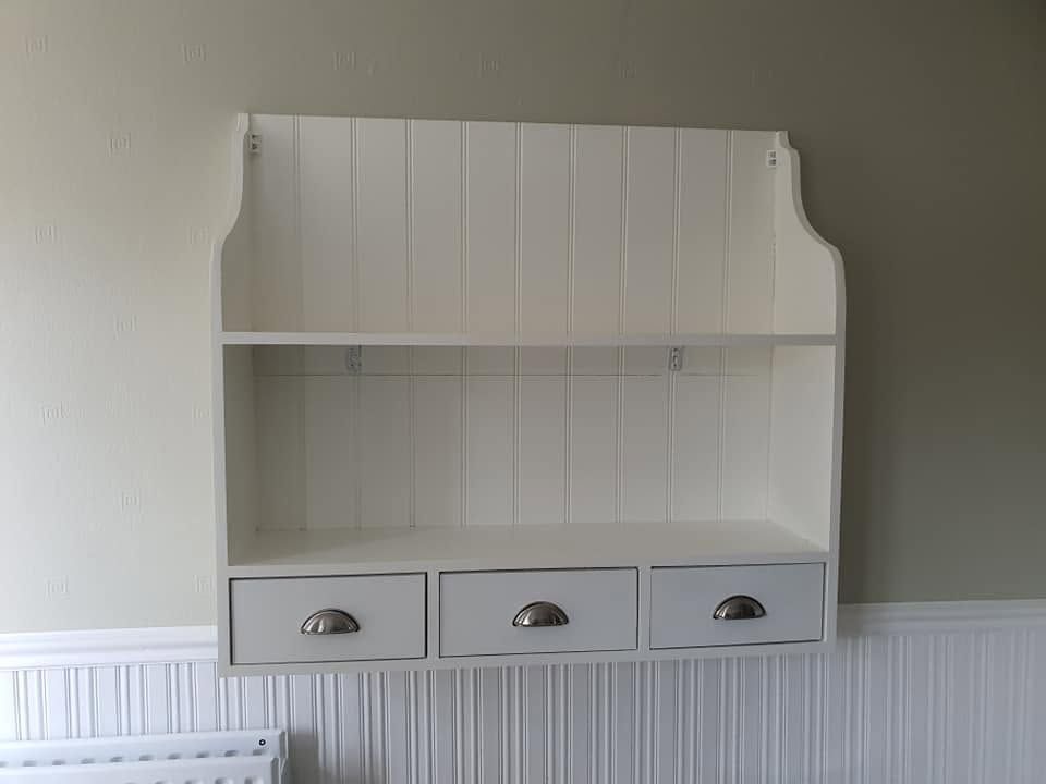 White painted wall shelf with tongue-and-groove back and three drawers with cup handles
