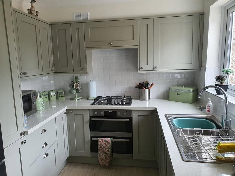 Sage green shaker kitchen with white metro tiles, light worktops and built-in double oven
