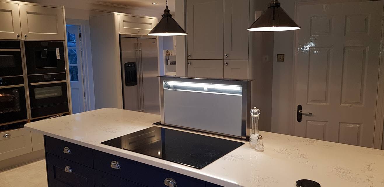 Navy kitchen island with white quartz worktop, induction hob and pop-up downdraft extractor under pendant lights