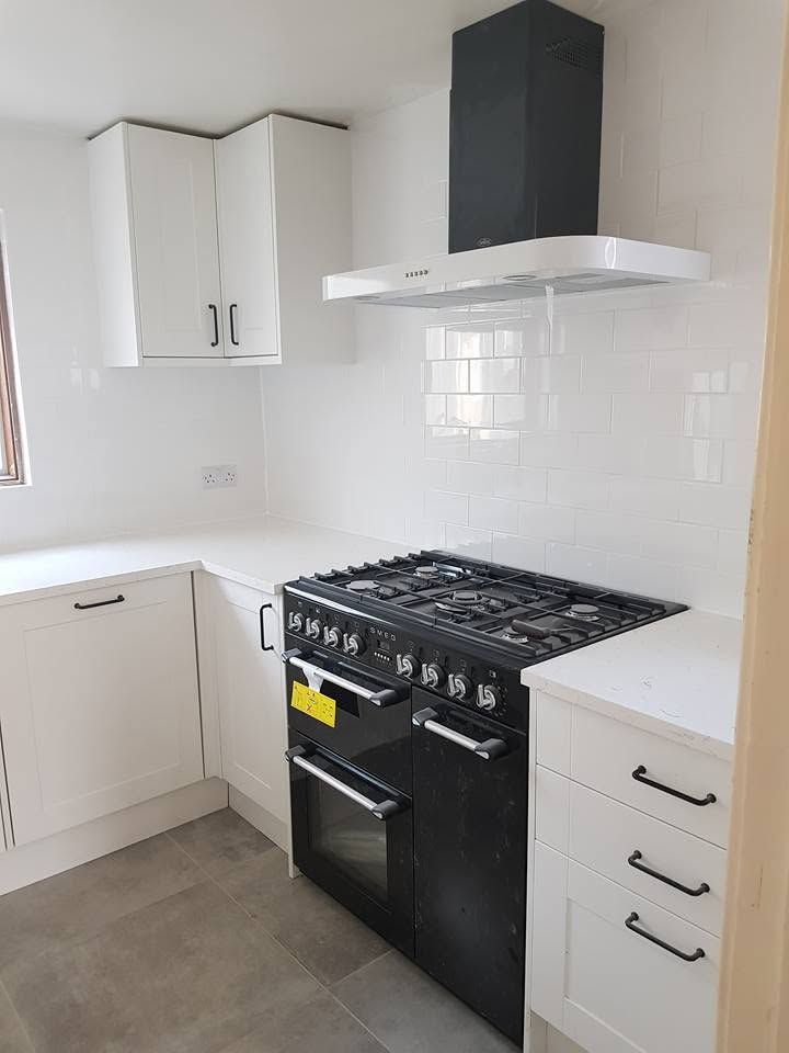 White shaker kitchen with black bar handles, metro tile splashback, black range cooker and chimney hood
